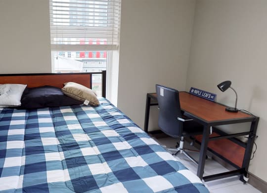 a bedroom with a bed and a desk and a window