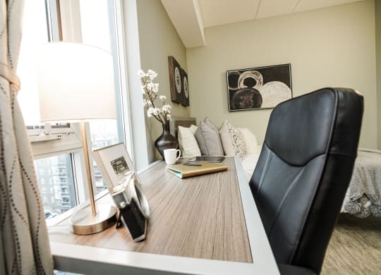 a bedroom with a desk with a chair and a window