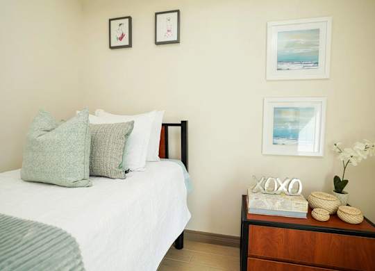 A bedroom with a bed, nightstand, and pictures on the wall.