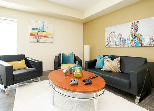 A living room with a black couch, a black chair, and a coffee table.