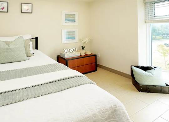 A bedroom with a large bed and a nightstand with a vase of flowers on it.