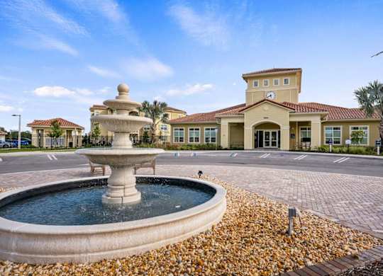 A fountain in the middle of a paved area in front of a building.