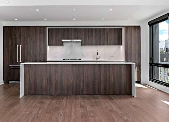 A modern penthouse kitchen with dark wood cabinets and a white countertop.