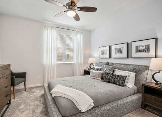 A bedroom with a bed, dresser, and ceiling fan.
