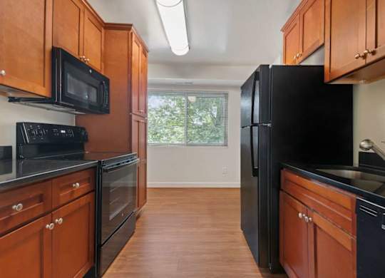 A kitchen with black appliances and wooden cabinets.