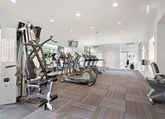 A gym with a variety of equipment including treadmills, weights, and exercise machines.