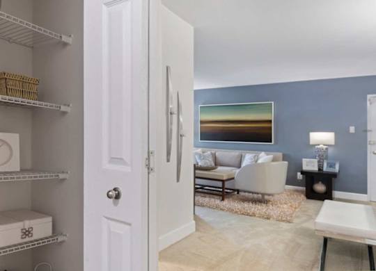 A white door is open to a living room with a couch and a painting on the wall.