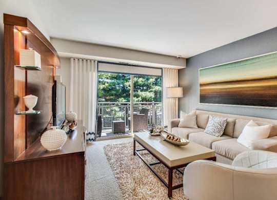 A modern living room with a wooden cabinet, a white sofa, a coffee table, and a large painting on the wall.