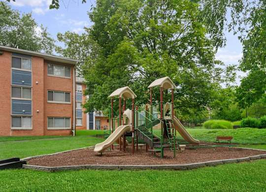 A playground with a slide and swings in a grassy area.
