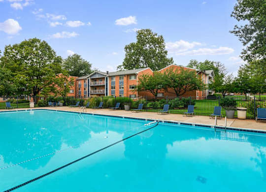 A large swimming pool in front of a building surrounded by trees.