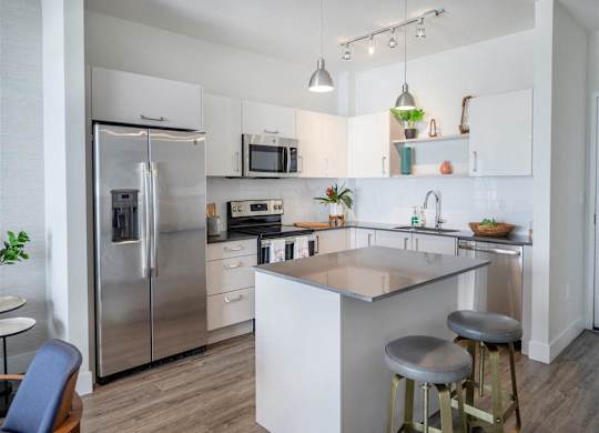 a kitchen with a center island and a stainless steel refrigerator