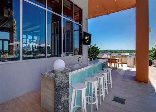 a bar with stools in front of a building with large windows