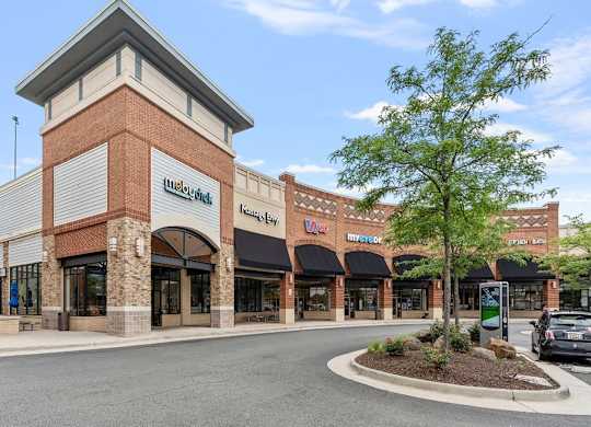 a store front of a brick building with a parking lot