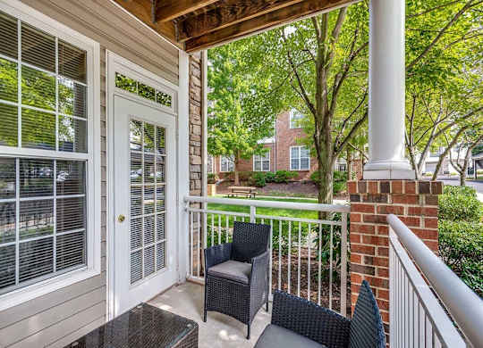 the front porch of a home with two chairs and a table