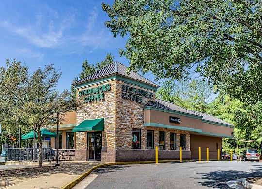 the facade of a restaurant with a street and trees