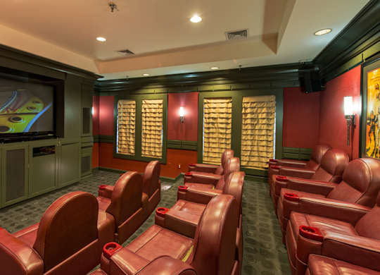 a screening room with red leather chairs and a television