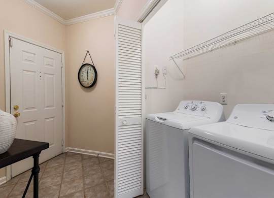a laundry room with a washer and dryer and a door to a closet