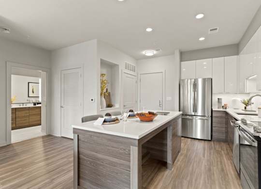 a kitchen with a large island and a stainless steel refrigerator