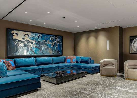 a curved seating area with blue chairs and a large mural on the wall