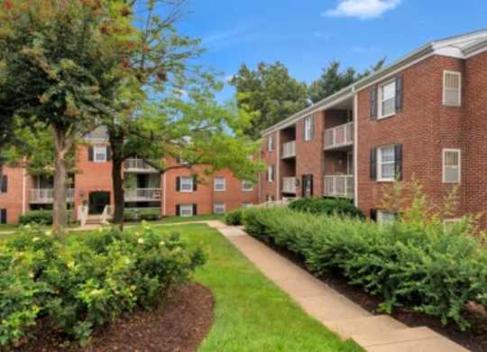 an exterior view of a brick apartment building with a sidewalk