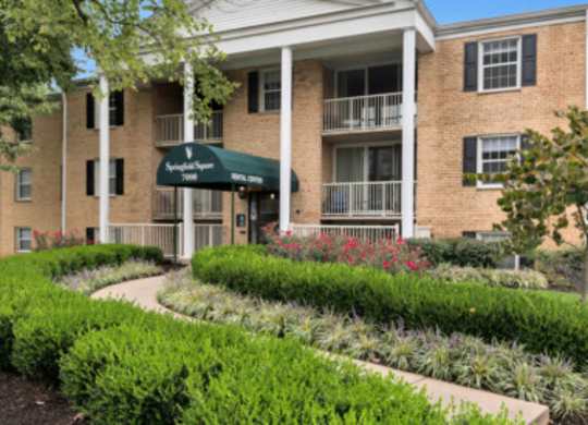 a brick building with a green awning and a garden in front of it
