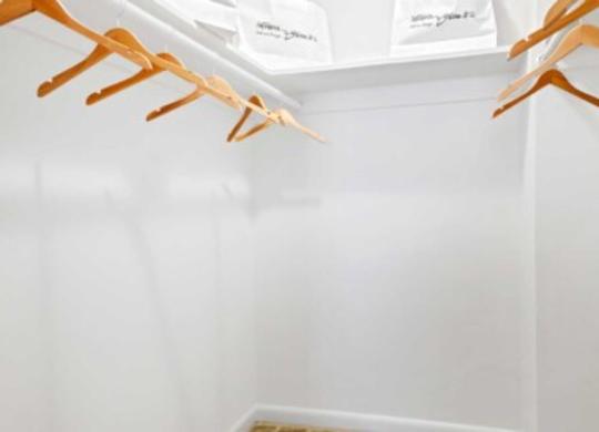 a white closet with wooden shoe racks on the wall