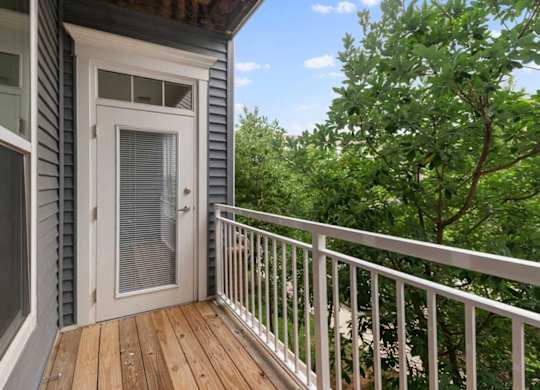 a balcony or terrace with a door and some trees
