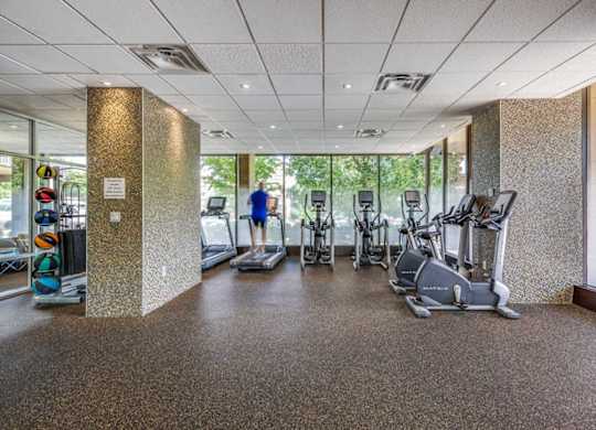 A gym with a variety of exercise equipment including treadmills, stationary bikes, and elliptical machines.