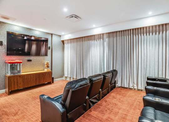 A home theater with black leather chairs and a wooden entertainment center.
