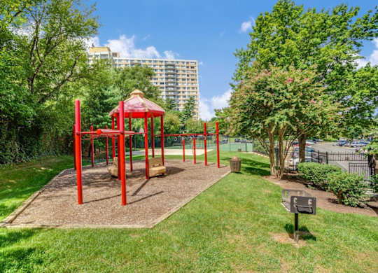 A playground with a red swing set and a sign in the foreground.