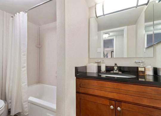 A bathroom with a toilet, a bathtub, a sink and a mirror.