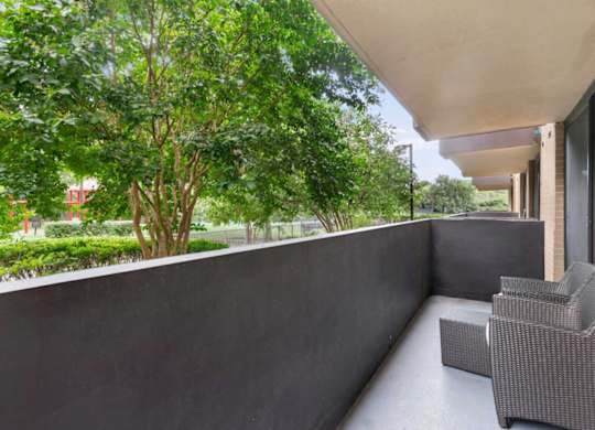 A balcony with a grey chair and a concrete wall.