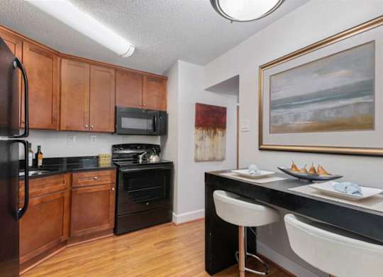 A kitchen with a black counter top and white chairs.