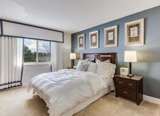 A bedroom with a large bed and a window with curtains.