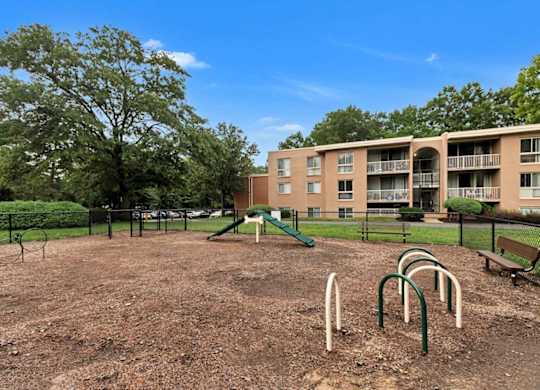 A playground with a green slide and a brown dirt ground.