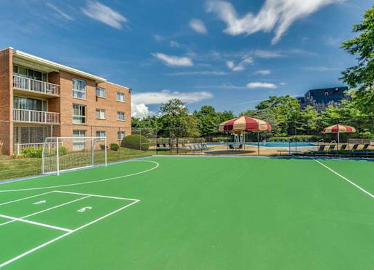 A tennis court is surrounded by apartment buildings.