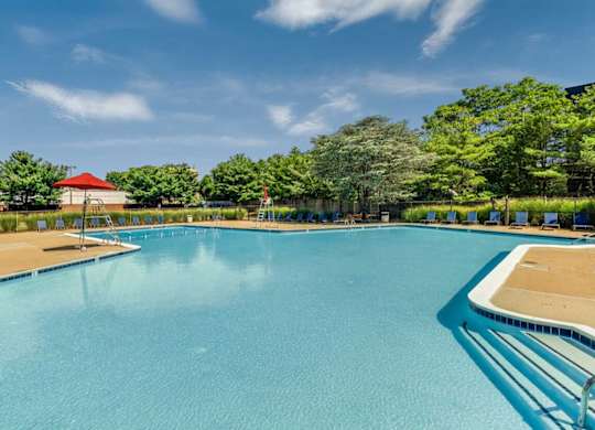 A large swimming pool with a red roof and trees in the background.