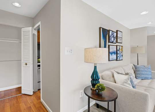 A living room with a white couch, a blue lamp, and a small table.
