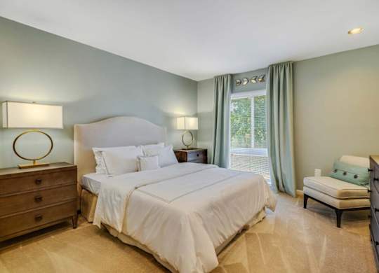 A bedroom with a large bed, two nightstands, and a window with curtains.