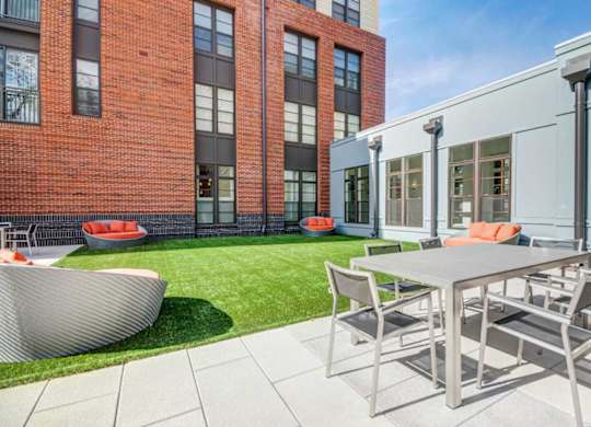 A modern outdoor dining area with a table and chairs.
