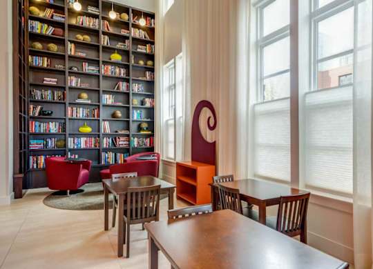 A children's room with a large bookshelf filled with books and a table with chairs.