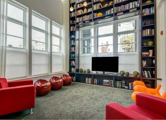 A living room with a large bookshelf filled with books and a flat screen TV.