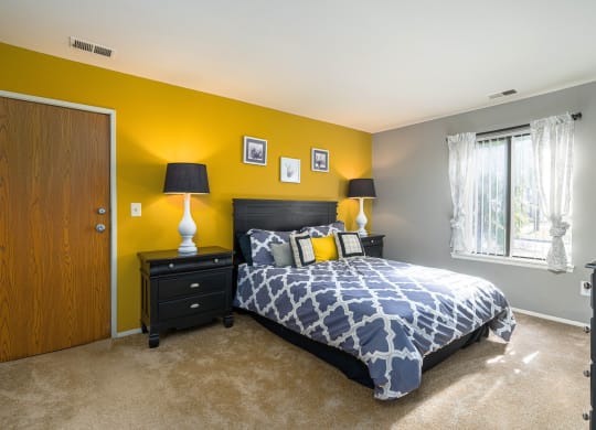 a bedroom with a bed and a yellow wall and a window