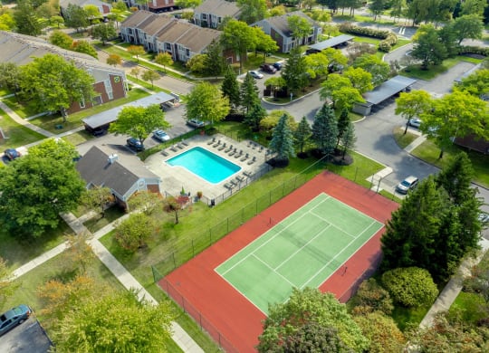 an aerial view of a tennis court and a swimming pool in a neighborhood with houses