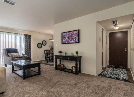 Comfortable living room with natural light and balcony access at Knottingham Apartments in Clinton Township, MI
