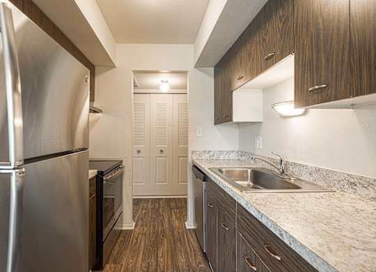Sleek kitchen with stainless steel appliances, granite countertops and custom cabinetry at Knottingham Apartments in Clinton Township, MI