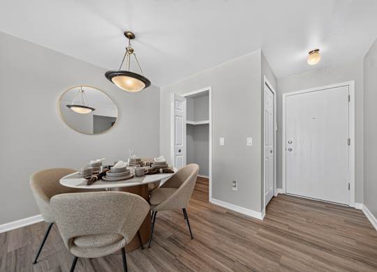 A dining room with a table set for two and a light fixture hanging from the ceiling.