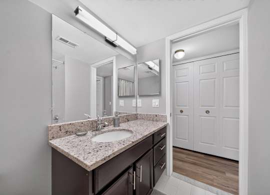 Modern bathroom with large vanity mirror and tub/shower at Lakeside Village Apartments in Clinton Township, MI