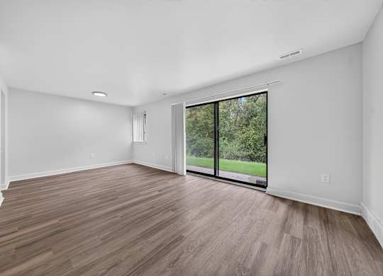 A room with a sliding glass door leading to a green outdoor area.