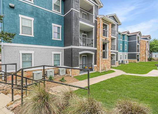 A multi-story apartment building with a green lawn in front.